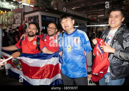 27. November 2022, Tokio, Japan: Costa-ricanische Touristen freuen sich, als ein japanischer Fußballfan beim Shibuya Scramble in Tokio schmeckt, nachdem Costa Rica Japan in einem Gruppenspiel der Katar-Weltmeisterschaft 2022 mit 1:0 besiegt hatte. Costa Rica und Japan sind jetzt auf Punkte gesetzt, aber Japan liegt vor dem Tor Differential und wetteift um einen Platz, um eine harte Gruppe E zu überleben und in die Achtelfinale aufzusteigen... Fußball, Fußball, FIFA-Weltmeisterschaft, japanische Fußballnationalmannschaft, Samurai Blue, Tokio. (Bild: © Taidgh Barron/ZUMA Press Wire) Stockfoto