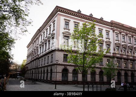 Iwano-Frankiwsk, Ukraine - 29. April 2025: Klassische Architektur auf einer europäischen Straße mit Bäumen und Kopfsteinpflastersteg Stockfoto