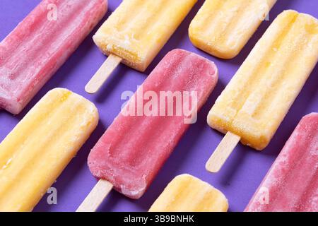 Rote Erdbeere und gelbe Stiele auf violettem Hintergrund Stockfoto