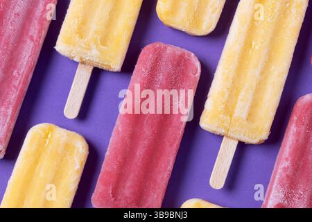 Rote Erdbeere und gelbe Stiele auf violettem Hintergrund Stockfoto