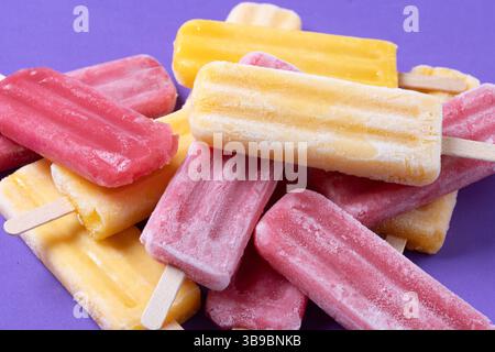 Rote Erdbeere und gelbe Stiele auf violettem Hintergrund Stockfoto