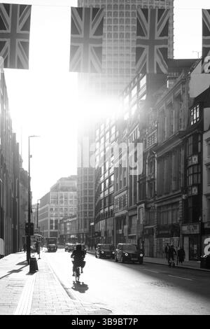 London, England - 28. April 2025: Die Morgensonne erleuchtet die Union Jacks, die über der Oxford Street in London hängen, als die ersten Pendler es schaffen Stockfoto