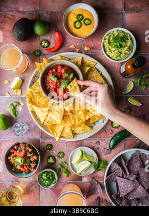 Blick von oben in Salsa mit Guacamole, Getränke auf Fliesen. Stockfoto