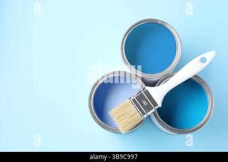 Dosen mit Farbe in Blautönen und Pinsel auf farbigem Hintergrund, Draufsicht. Leerzeichen für Text Stockfoto