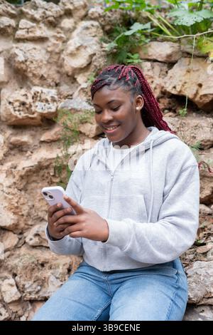 Junge schwarze Frau mit Smartphone im Park Stockfoto