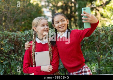 Zwei lächelnde Schüler machen draußen ein Selfie mit Smartphone Stockfoto