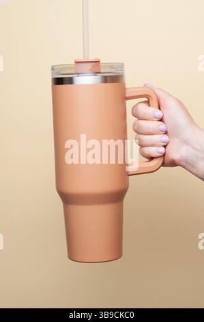 Weibliche Hand, die einen 40-ml-Becher hält. Reisebecher Strohabdeckungen Becher mit Deckel Stockfoto