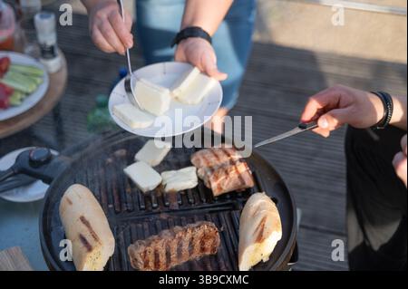 Genießen Sie unvergessliche Momente mit gegrilltem Fleisch, reichhaltigem Käse und frischen Beilagen bei einem Grill im Freien mit Freunden und Familie Stockfoto