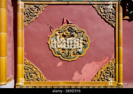 Detailliertes Relief des chinesischen Drachen auf einer Roten Mauer in der Verbotenen Stadt, das traditionelle Symbolismus hervorhebt Stockfoto