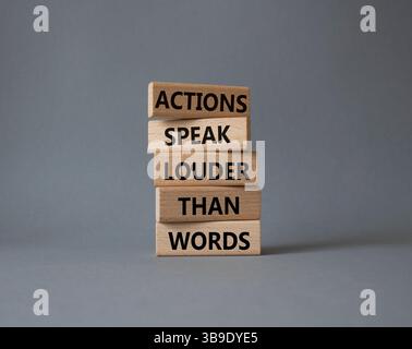 Taten sprechen lauter als Wörter. Holzblöcke mit Worten Aktionen sprechen lauter als Worte. Schöner grauer Hintergrund. Business and Actions conc Stockfoto