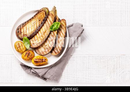 Gegrillte Zucchini und Babykartoffeln auf einer Keramikplatte, in rustikaler flacher Ladefläche gefangen, perfekt für eine gesunde und aromatische pflanzliche Basis Stockfoto