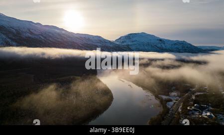 Wunderschöne Flußkulisse in Nordnorwegen, bedeckt mit Wolken und Nebel, umgeben von Bergen. Winding River wurde auf eine Drohne geschossen. Stockfoto