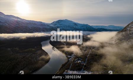 Wunderschöne Flußkulisse in Nordnorwegen, bedeckt mit Wolken und Nebel, umgeben von Bergen. Winding River wurde auf eine Drohne geschossen. Stockfoto