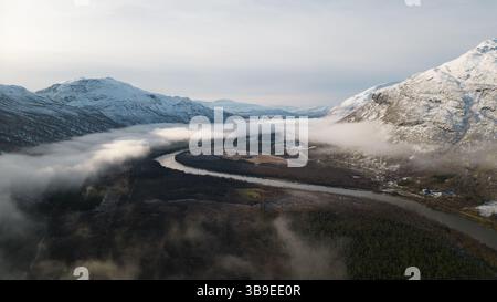 Wunderschöne Flußkulisse in Nordnorwegen, bedeckt mit Wolken und Nebel, umgeben von Bergen. Winding River wurde auf eine Drohne geschossen. Stockfoto