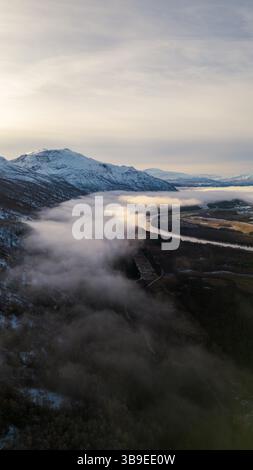 Wunderschöne Flußkulisse in Nordnorwegen, bedeckt mit Wolken und Nebel, umgeben von Bergen. Winding River wurde auf eine Drohne geschossen. Stockfoto