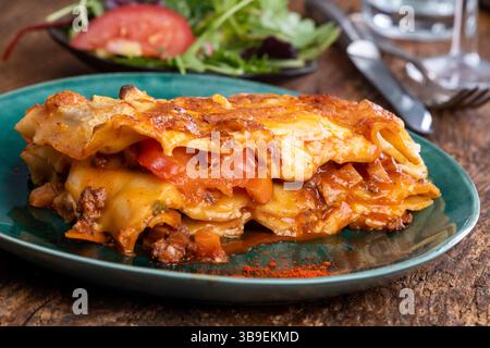 Lasagne auf grünem Teller mit Salat Stockfoto