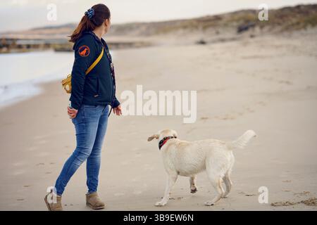 Aktive Frau mit Hund am Strand Stockfoto