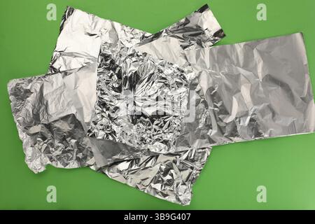 Zerknitterte Aluminiumfolien auf grünem Hintergrund, Draufsicht Stockfoto