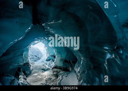 Ein faszinierender Blick aus einer Eishöhle am Katla-Gletscher, Island. Die glatten, blauen Wände des gefrorenen Tunnels öffnen sich zu einer schneebedeckten Landschaft Stockfoto