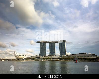 Atemberaubender Blick auf das Marina Bay Sands Hotel und das ArtScience Museum vor einem bewölkten Himmel in Singapur, mit moderner Architektur und einem ruhigen Wasser Stockfoto