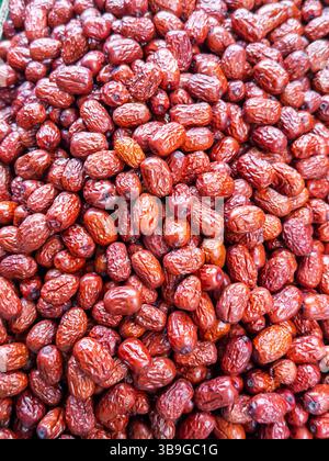 Eine lebendige Nahaufnahme glänzender roter Jujube-Früchte, frisch geerntet und auf einem lokalen Markt in Singapur zum Verkauf angeboten. Stockfoto