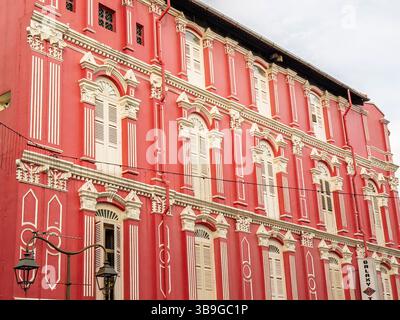 Komplexe architektonische Details eines historischen Gebäudes mit einer markanten roten Fassade in Singapur. Das Gebäude zeigt traditionelle Kolonialgebäude Stockfoto