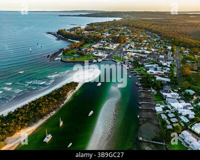 Ein atemberaubender Blick aus der Luft auf eine Küstenstadt mit einem gewundenen Fluss, unberührtem Strand, üppigem Grün und Wohngebäuden, die die ruhige Schönheit A einfangen Stockfoto