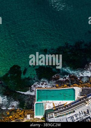 Ein atemberaubender Blick aus der Vogelperspektive fängt den Pool am Meer in Sidney, Australien, ein. Türkisfarbenes Wasser trifft auf felsige Küsten und schafft eine Harmonie Stockfoto