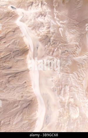 Ein Blick aus der Vogelperspektive auf Dünen, die sich durch die Wüste schlängeln und natürliche Erosion und Sandformationen zeigen. Die Szene zeigt das trockene Land. Stockfoto