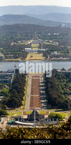 Luftaufnahme, die das weitläufige Layout von Canberra mit dem Parlamentsgebäude im Hintergrund einfängt, umgeben von üppigem Grün und dem Canberra Stockfoto