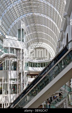 Innenansicht eines Einkaufszentrums mit Rolltreppe, Aufzügen und Glasdecke. Überwiegend weiß und hell im Bentall Centre in Kingston, Großbritannien. Stockfoto