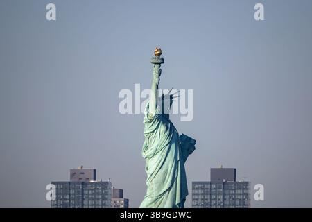 Ikonischer Blick auf die Freiheitsstatue vor einer Skyline des Gebäudes in New York, die einen ruhigen Moment mit klarem Himmel festhält. Stockfoto