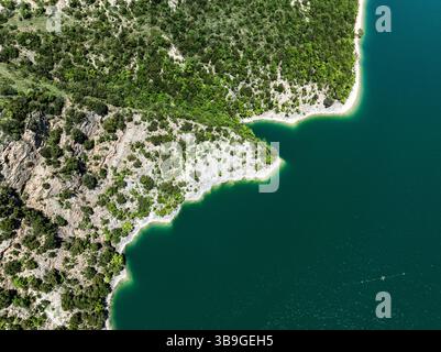 Luftaufnahme mit dem leuchtend grünen Laub und der felsigen Küste des Lago di Fiastra, Italien. Das kristallklare Wasser unterstreicht das atemberaubende natura Stockfoto