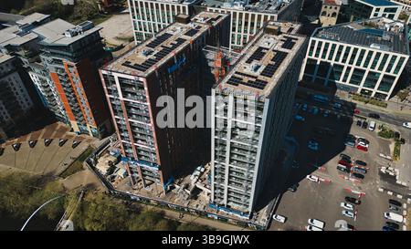 Die Luftaufnahme zeigt Hochhäuser, einige im Bau, mit Parkplätzen und Straßen voller Autos in einer modernen städtischen Umgebung in Leeds. Stockfoto
