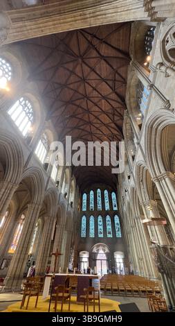 Innenansicht einer Kathedrale mit gotischer Architektur, Holzdecke, Buntglasfenstern und Altar. Stockfoto