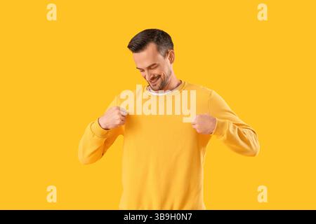 Junger Mann im Sweatshirt auf gelbem Hintergrund Stockfoto