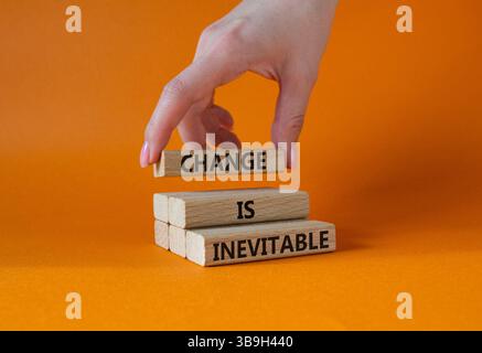 Veränderung ist ein unvermeidbares Symbol. Holzklötze mit Worten Veränderung ist unvermeidlich. Wunderschöner orangefarbener Hintergrund. Geschäftsmann Hand. Business and Change ist Inev Stockfoto