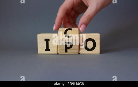 ICO vs. IPO-Symbol. Geschäftsmann Hand dreht Holzwürfel und ändert das Wort IPO in ICO. Schöner grauer Hintergrund. ICO vs IPO und Geschäftskonzept. Co Stockfoto