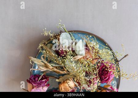Getrocknete Rosenblüten liegen als buntes Blumenarrangement auf einem türkisfarbenen Teller Stockfoto