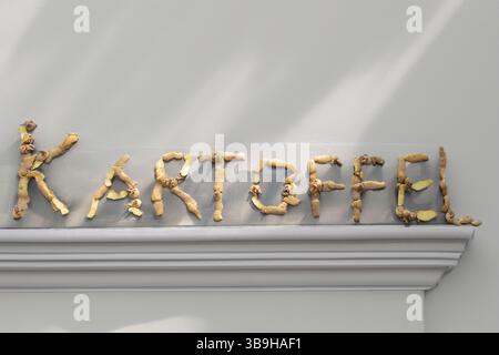 Das Wort Kartoffel ist in Form von Schalen auf grauem Hintergrund zum Thema Bio-Abfall und gesunde Ernährung Stockfoto