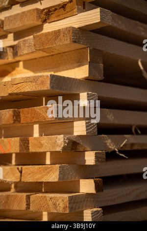 Detaillierte Ansicht von frisch gesägten Holzdielen im Freien, mit Körnung, Textur und groben Kanten bei warmem goldenem Sonnenlicht mit sichtbaren Faserstoffen Stockfoto