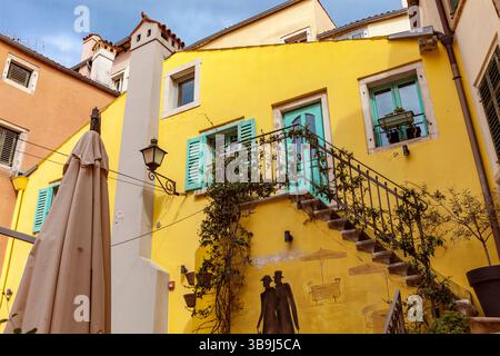 Traditionelle venezianische Fensterläden, Wandgemälde und Außentreppe in einem farbenfrohen Innenhof in Rovinj, Istrien, Kroatien Stockfoto