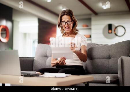 Der Buchhalter, Der Eine Schockierende Rechnung Auf Einem Laptop Überprüft, Fühlt Sich Überfordert Und Gestresst. Stockfoto