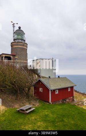 Alter Leuchtturm auf einer felsigen Klippe am Meer in Kullen, Schweden. Bewölkter Frühlingstag an der Küste. Stockfoto