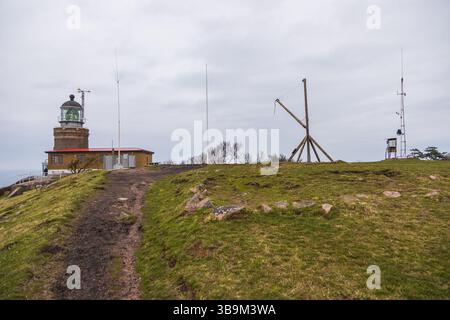 Alter Leuchtturm auf einer felsigen Klippe am Meer in Kullen, Schweden. Bewölkter Frühlingstag an der Küste. Stockfoto