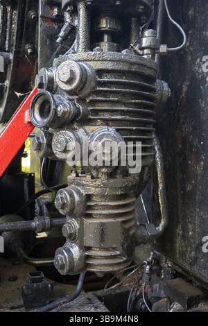 Ein rostiger alter Motor mit rotem Griff. Der Motor ist mit Schmutz und Schmutz bedeckt. Der rote Griff ist am Motor befestigt und dient zum Einschalten und Stockfoto