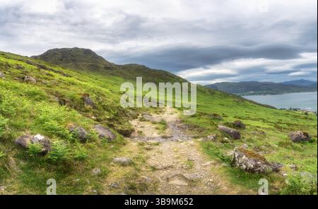 Tauchen Sie ein in die ruhige Schönheit der Natur, indem Sie einen atemberaubenden Wanderweg mit Slieve Foye, lebhaftem Grün und malerischem Wasser erkunden Stockfoto