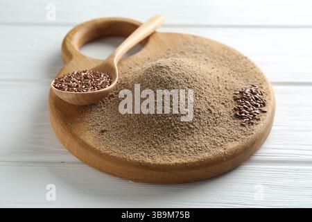 Leinsamenmehl und Löffel mit Samen auf weißem Holztisch, Nahaufnahme Stockfoto