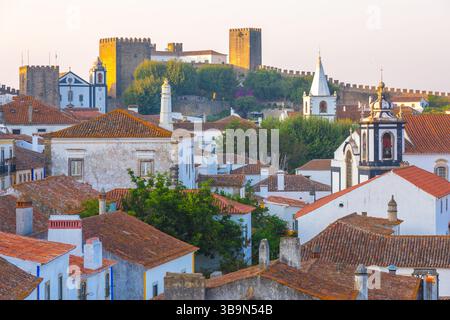 Obidos, Portugal: Ein malerischer Blick auf die mittelalterliche Stadt und das Schloss bei Sonnenuntergang Stockfoto