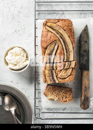 Butter, Zucker-freien Bananenbrot mit Hafermehl, weiche Quark und Honig. Blick von oben auf die bananenscheiben Brot auf grauzement Hintergrund. Ideen und Stockfoto